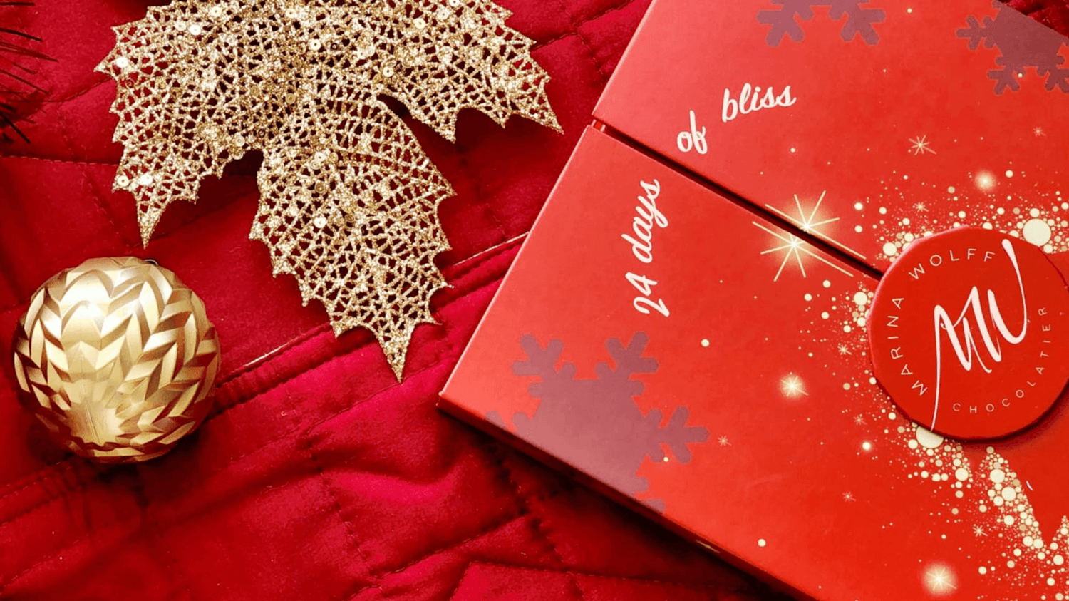 Red box that says 24 days of bliss on a red background beside Christmas ornaments