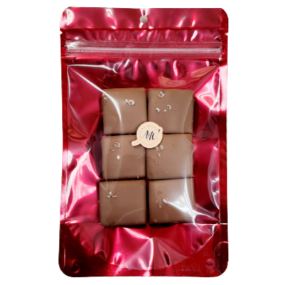 Red stand-up pouch with six chocolate squares with grains of salt on top of it.